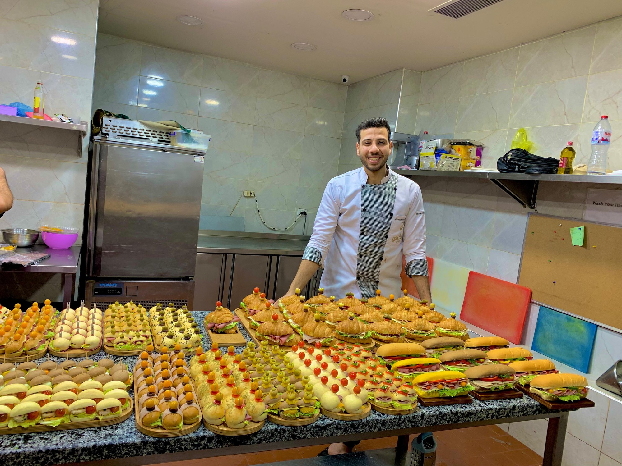 Chef Mohamed Elbishy standing behind a full table of pastries and canapés
